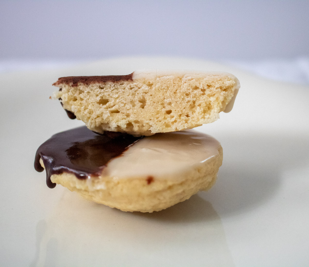 two vegan black and white cookies on white plate